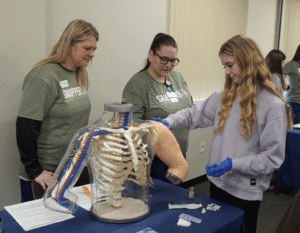 nursing students explain how to give injections to a high school visitor during a Healthcare Exploration event