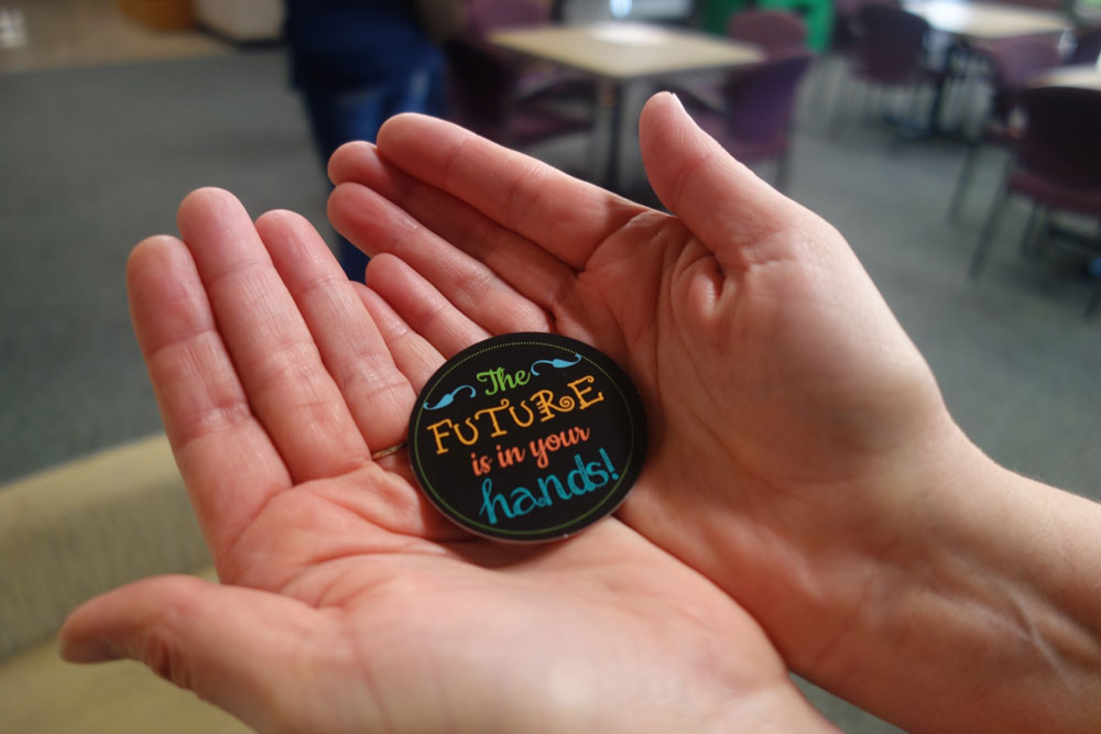 A pair of hands held together holding a button that says "The Future is in your hands!"