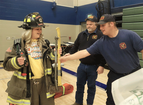 Coperas Creek fire department members help student try on heavy firefighting gear
