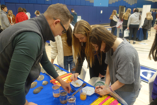 Students examine fish eggs on display at Jake Wolf Fish Hatchery table