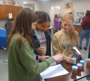 Three female students participating at a booth at College Visit Day event