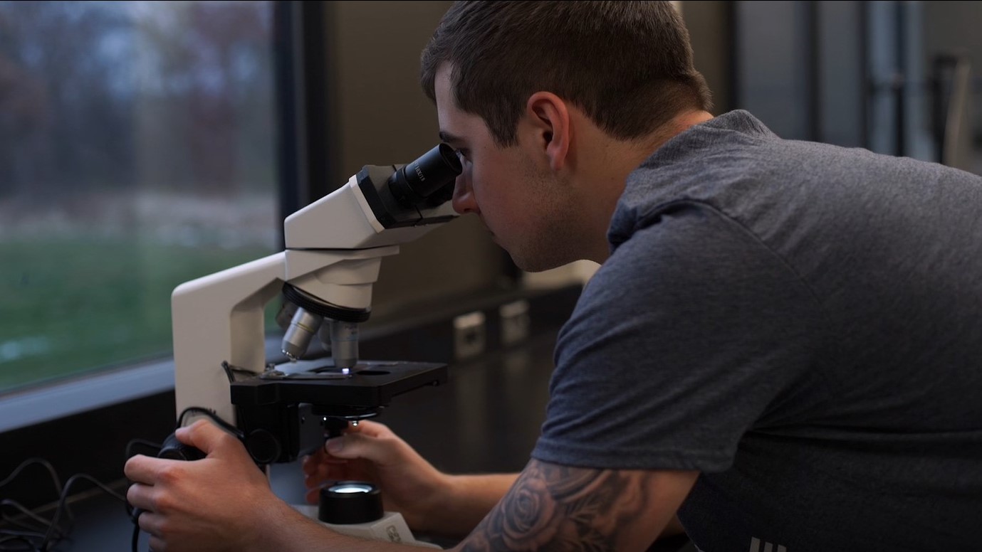 Male student using microscope