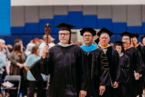 Image of senior faculty member Douglas Okey leading the processional during the Spoon River College Commencement