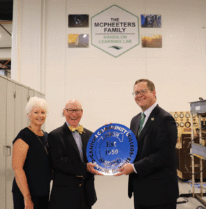 Denise and Lynn McPheeters being presented a metal sign from Dr. Curt Oldfield during the ribbon cutting held May 7.