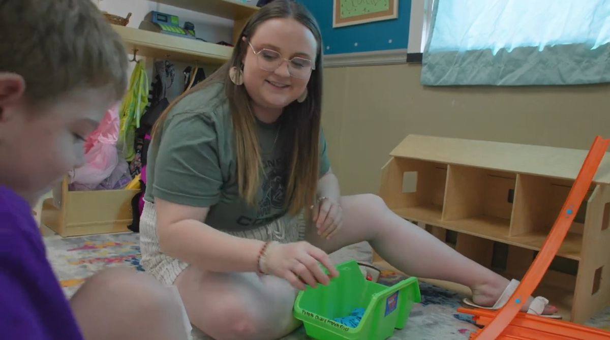 Female early childhood teacher/student with little boy, playing together in a preschool setting.