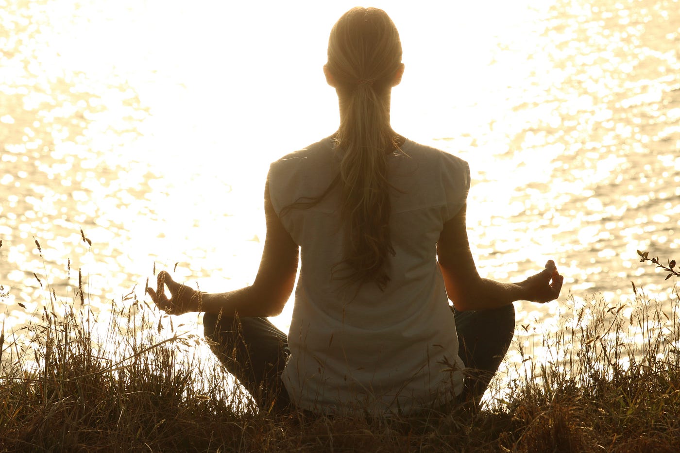 Image of woman meditating next to a lake