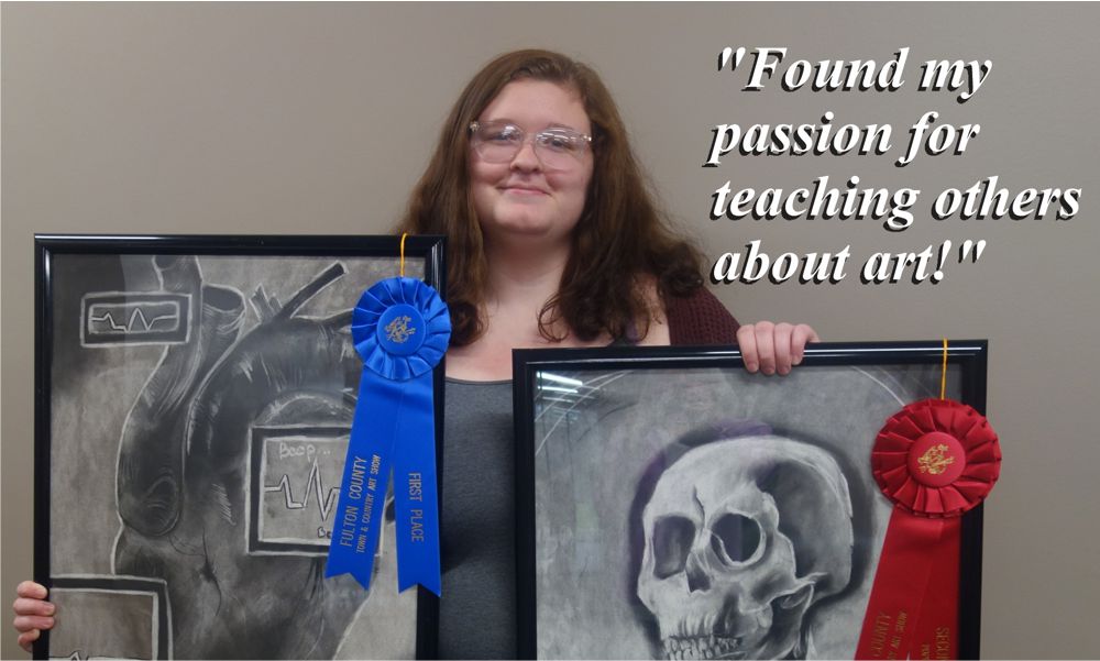 Image of Melody Barnes holding two paintings, one with a blue ribbon, the other with a red ribbon, and the text reading: "Found my passion for teaching others about art!"