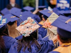 Close up of the back of a student's graduation cap, which is decorated with roses and says, she eaRNed it--emphasizing the RN in 'earned'