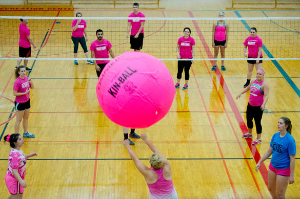 Students in gymnasium playing MEGA vollleyball with an enormous pink ball