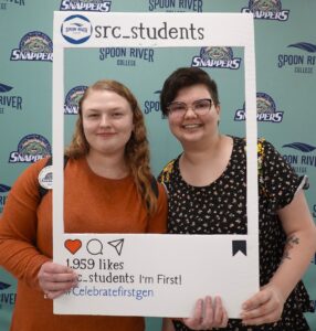 Two students posing inside a photo frame with text: src_students at the top, and social media information below: 1959 likes, src_students I'm First!, #Celebratefirstgen