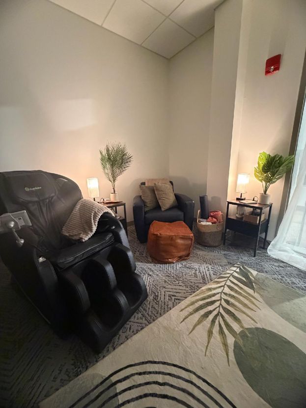 SRC Wellness Room Macomb campus--image of a cozy setting with lounge chairs, including a massage chair, plants, and various resources.